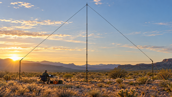 Vertical wire Delta Loop antenna deployed in an open high-desert field at golden hour